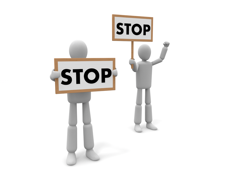 「STOP」と書かれた標識をそれぞれ掲げている2体の白い3D人物のイラスト。手前に一体、奥にもう一体が立っている。注意喚起や停止を強く促すイメージ。