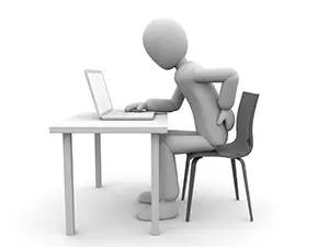 デスクでノートパソコンに向かい、片手で腰を押さえて痛がっている白い3D人物のイラスト